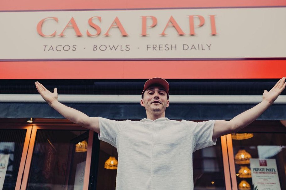 Casa Papi team member celebrating outside the shop under the backlit CASA PAPI sign, Bramhall